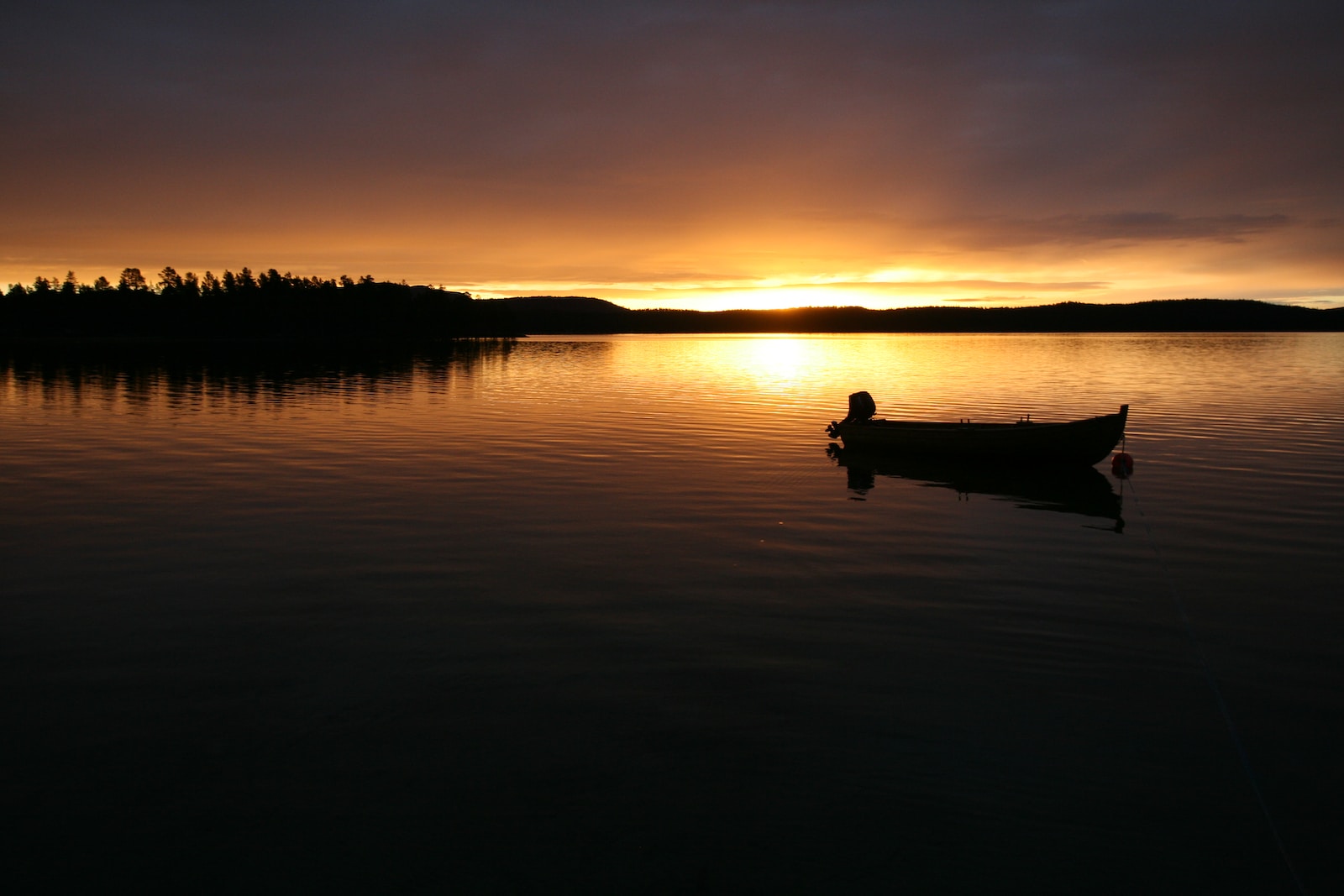 silhouette of man riding canoe on lake during sunset